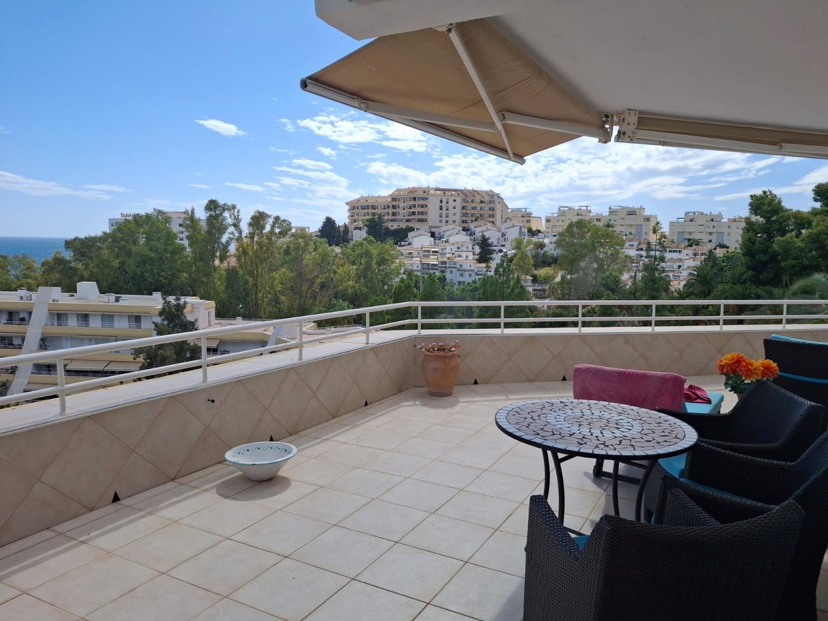 Spacious terrace with seating, mosaic table, and expansive view of the sea and town.