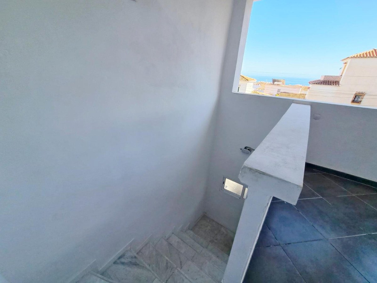 Staircase leading to a balcony with a view of the sea and buildings.