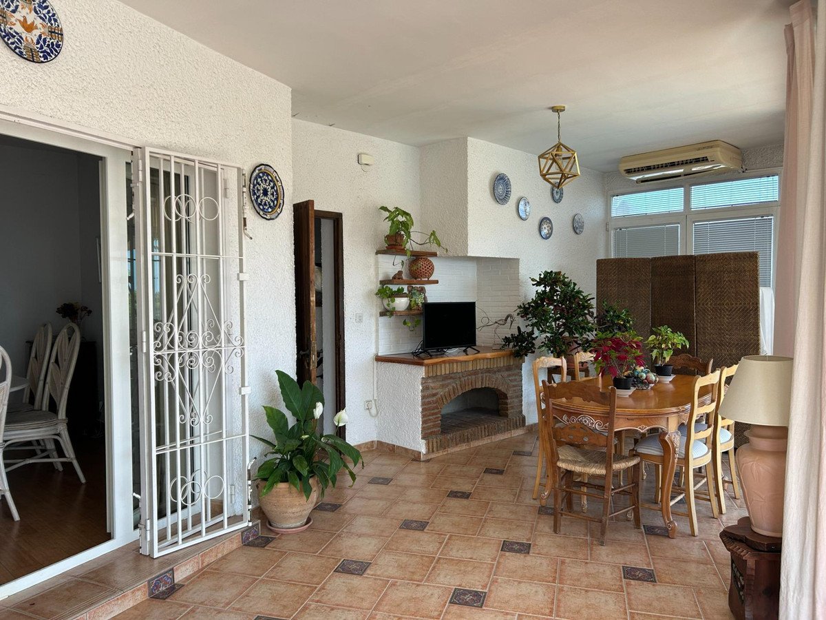 Spacious covered terrace with dining area, fireplace, and decorative plates on the wall.
