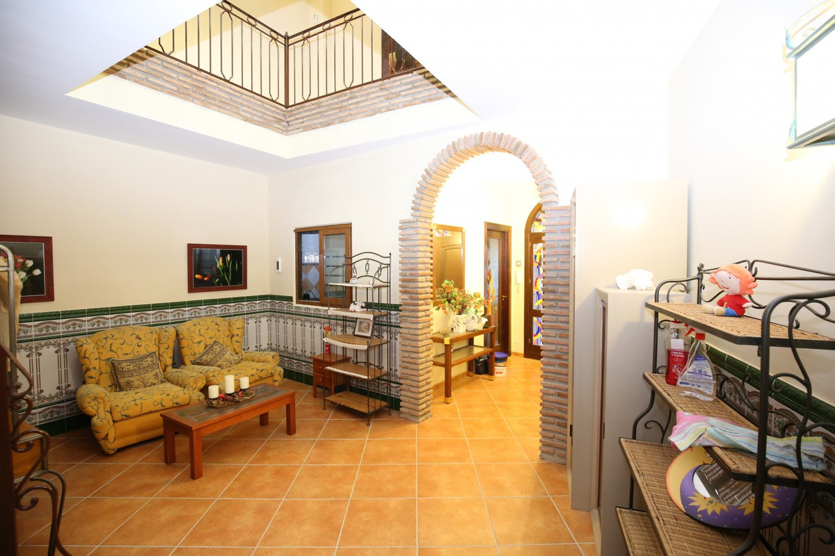 Eclectisch interieur met bakstenen boog, gele zitplaatsen en open balkon.