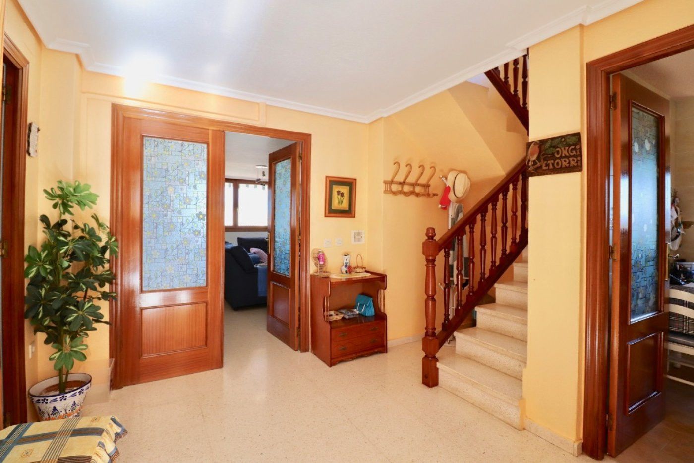 Interieur van een huis met een hal, trap en houten details.