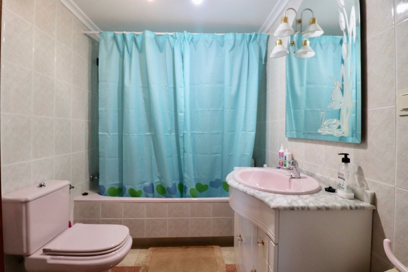 Badkamer met roze wastafel en blauw douchegordijn