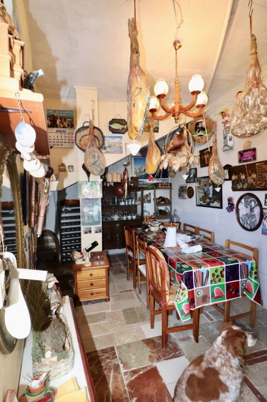 Excentrieke eetkamer met gedroogde hammen en een patchwork tafelkleed.