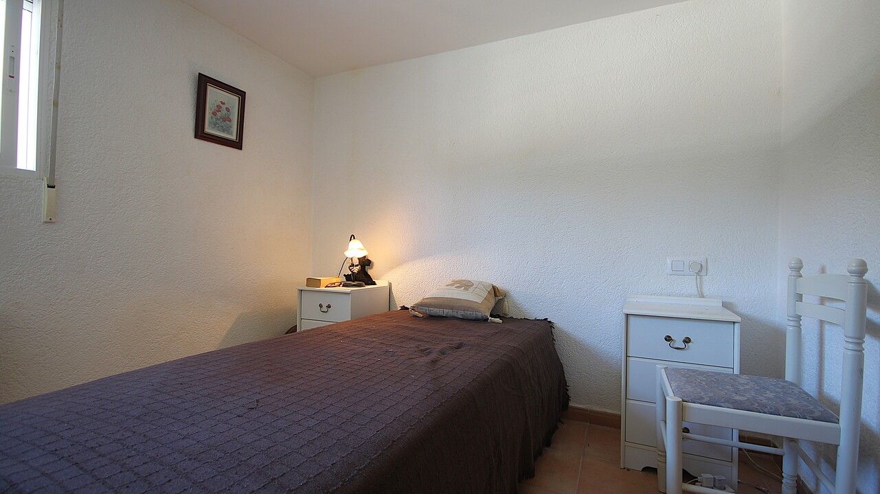 Kleine slaapkamer interieur met een bed, nachtkastjes en een stoel.