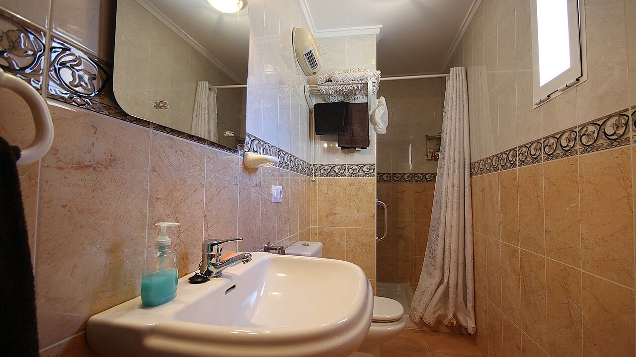 Badkamer met toilet, wastafel en douchecabine met douchegordijn