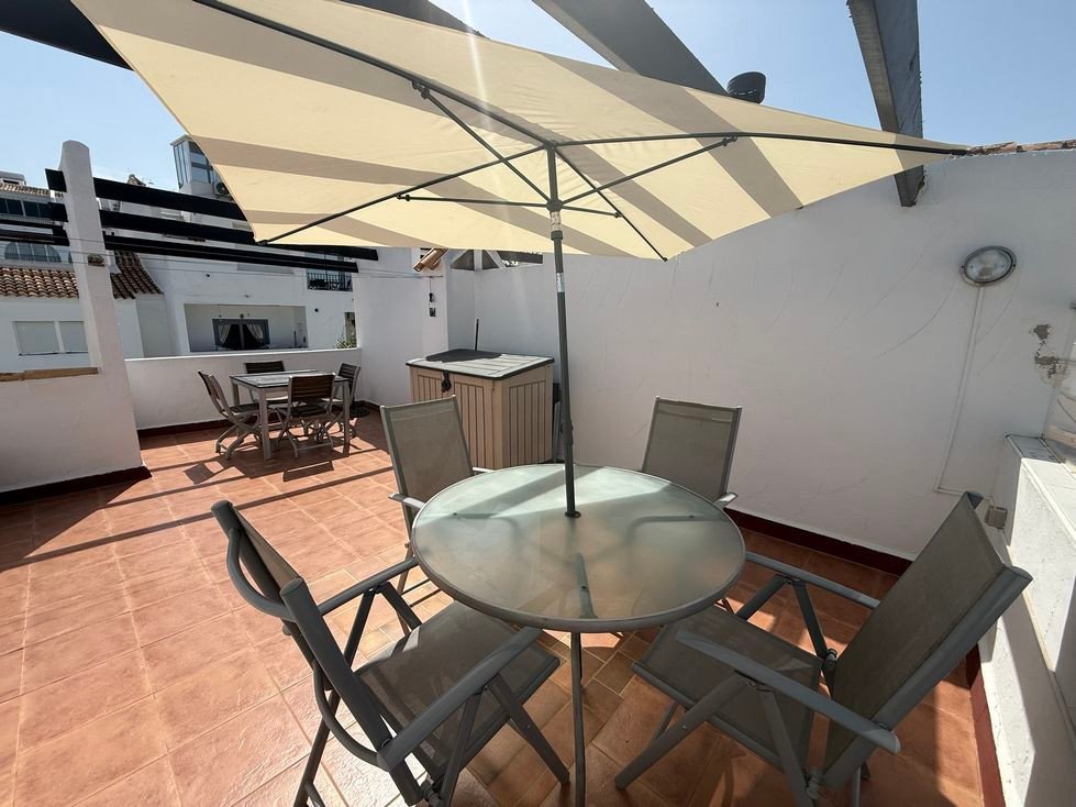 Outdoor terrace with a dining table, chairs, and an umbrella, perfect for al fresco meals.