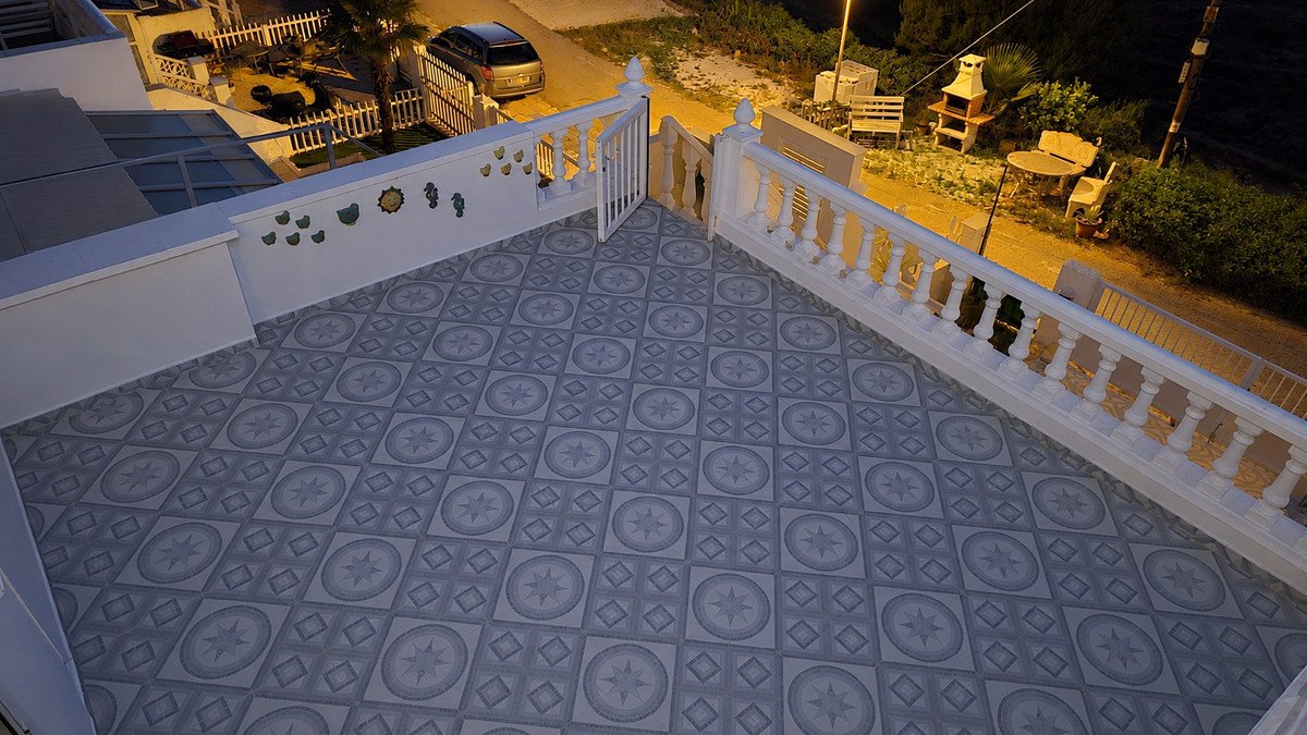 Tiled terrace with outdoor seating area, grill, and view of a car and garden path.