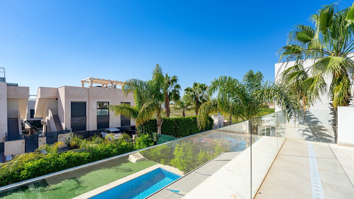 Modern villa with private pool, surrounded by lush greenery and palm trees under a clear blue sky.