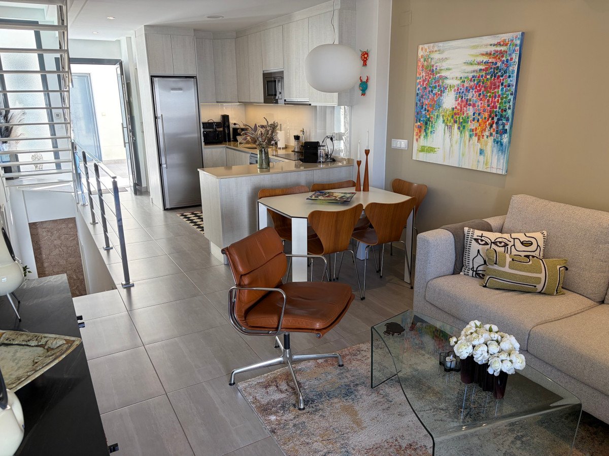 Modern open-plan living area with a sofa, dining table, modern kitchen, and artwork on the wall.