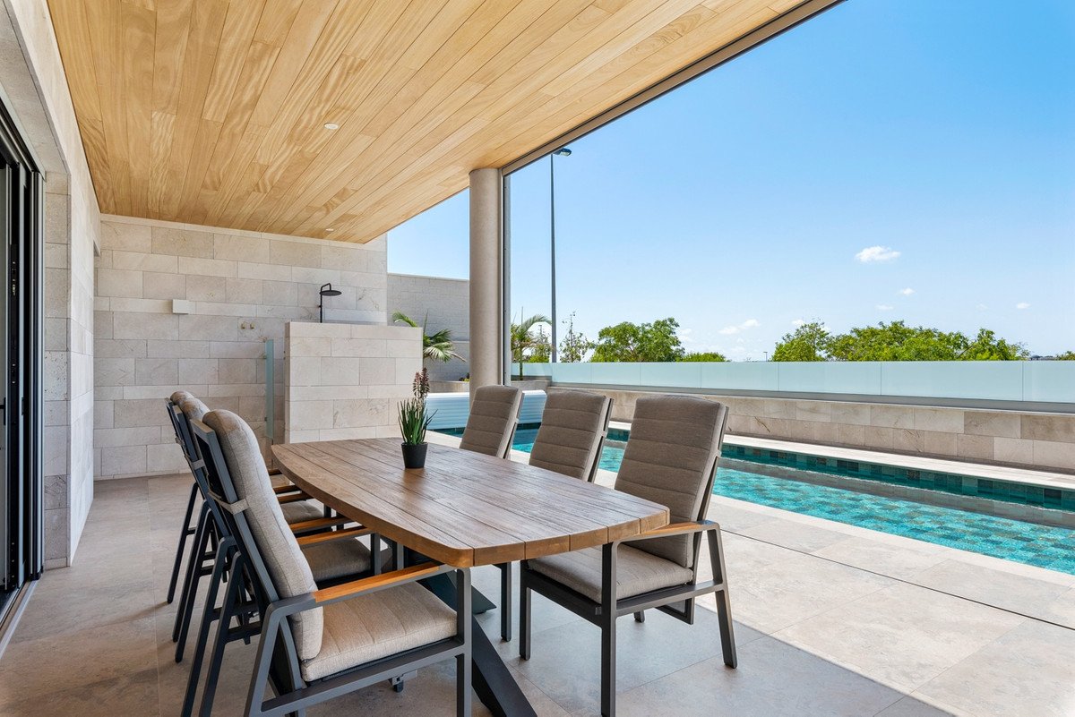 Modern dining room with wooden table and chairs overlooking a swimming pool