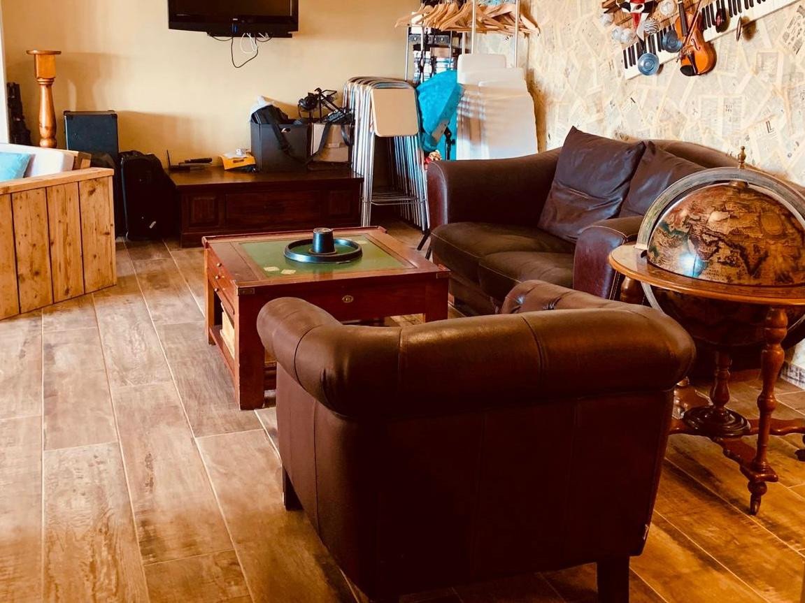 Cozy living room with leather armchair, sofa, wooden coffee table, and globe on tiled floor.
