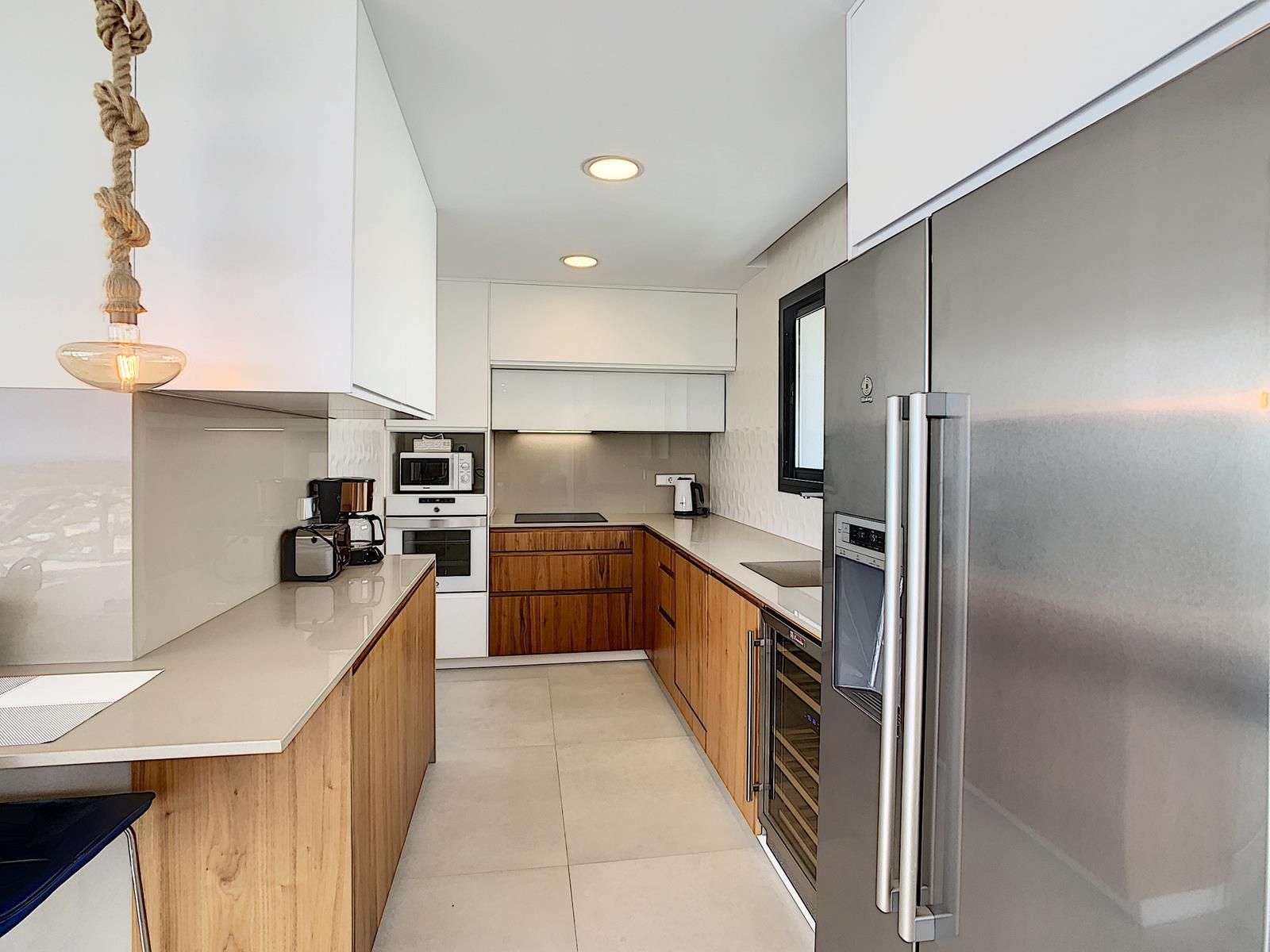 Moderne keuken met houten kasten en roestvrijstalen apparaten.