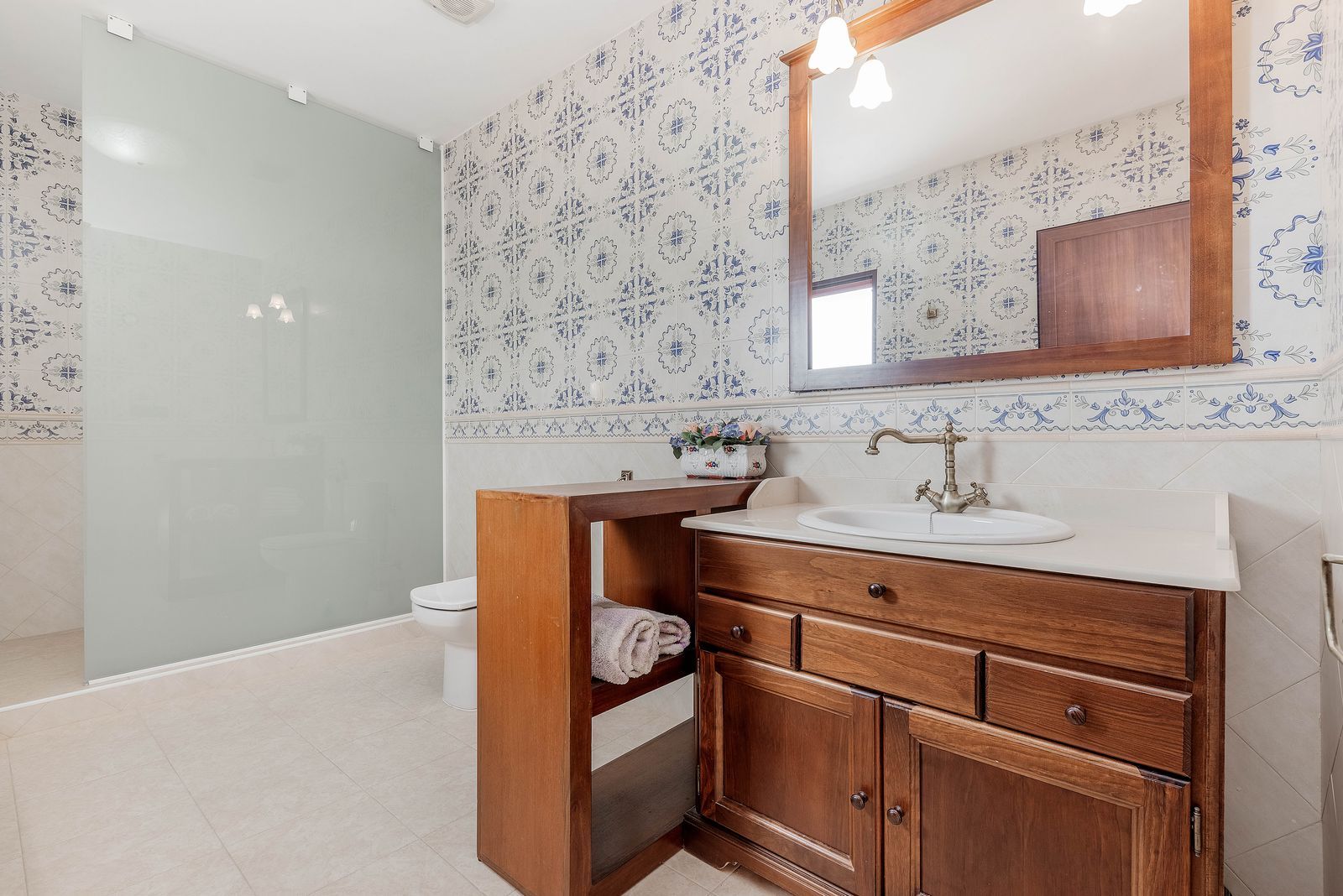 Badkamer met houten kast, blauwe tegels en wastafel.