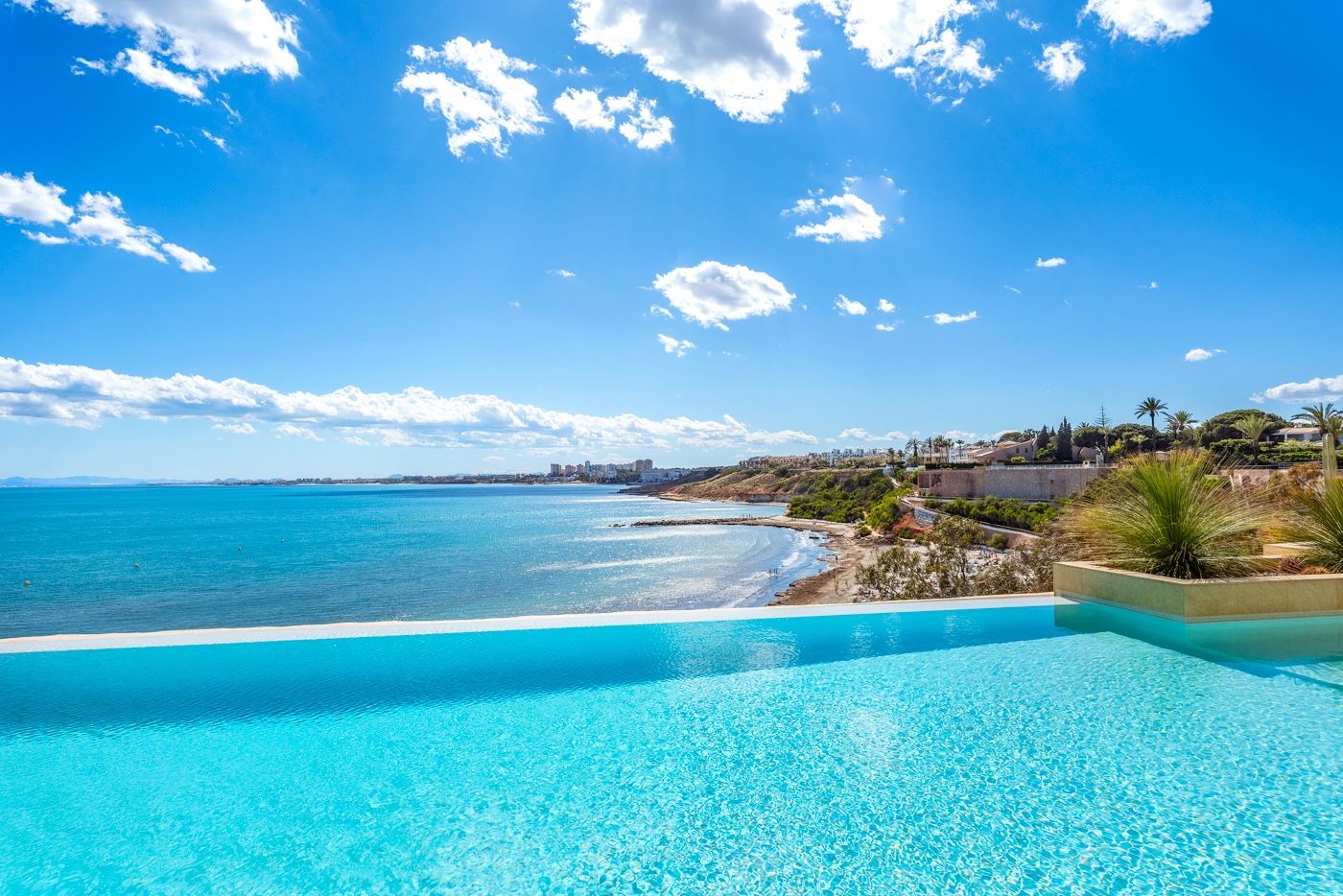 Infinity pool met uitzicht op de oceaan en helderblauwe hemel.