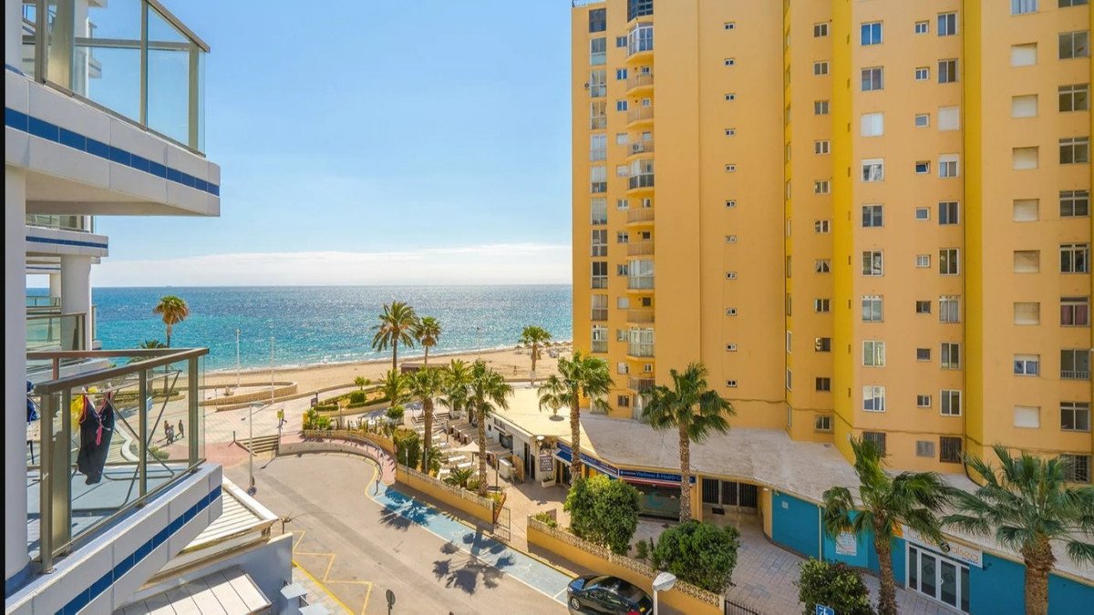 Sea view apartment with balcony overlooking beach, palm trees, and ocean from high-rise building.