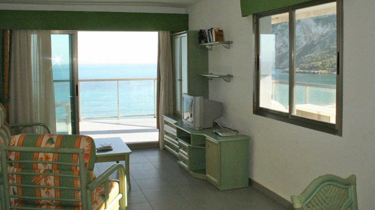 Living room with ocean view, green furniture, TV, and balcony access.