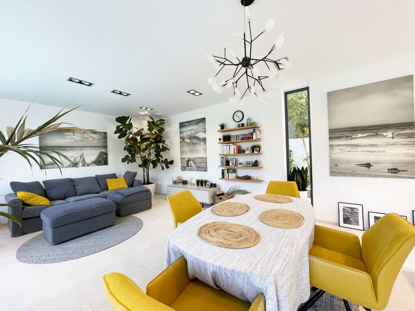 Moderne woon-eetkamer met grijze bank en gele stoelen.