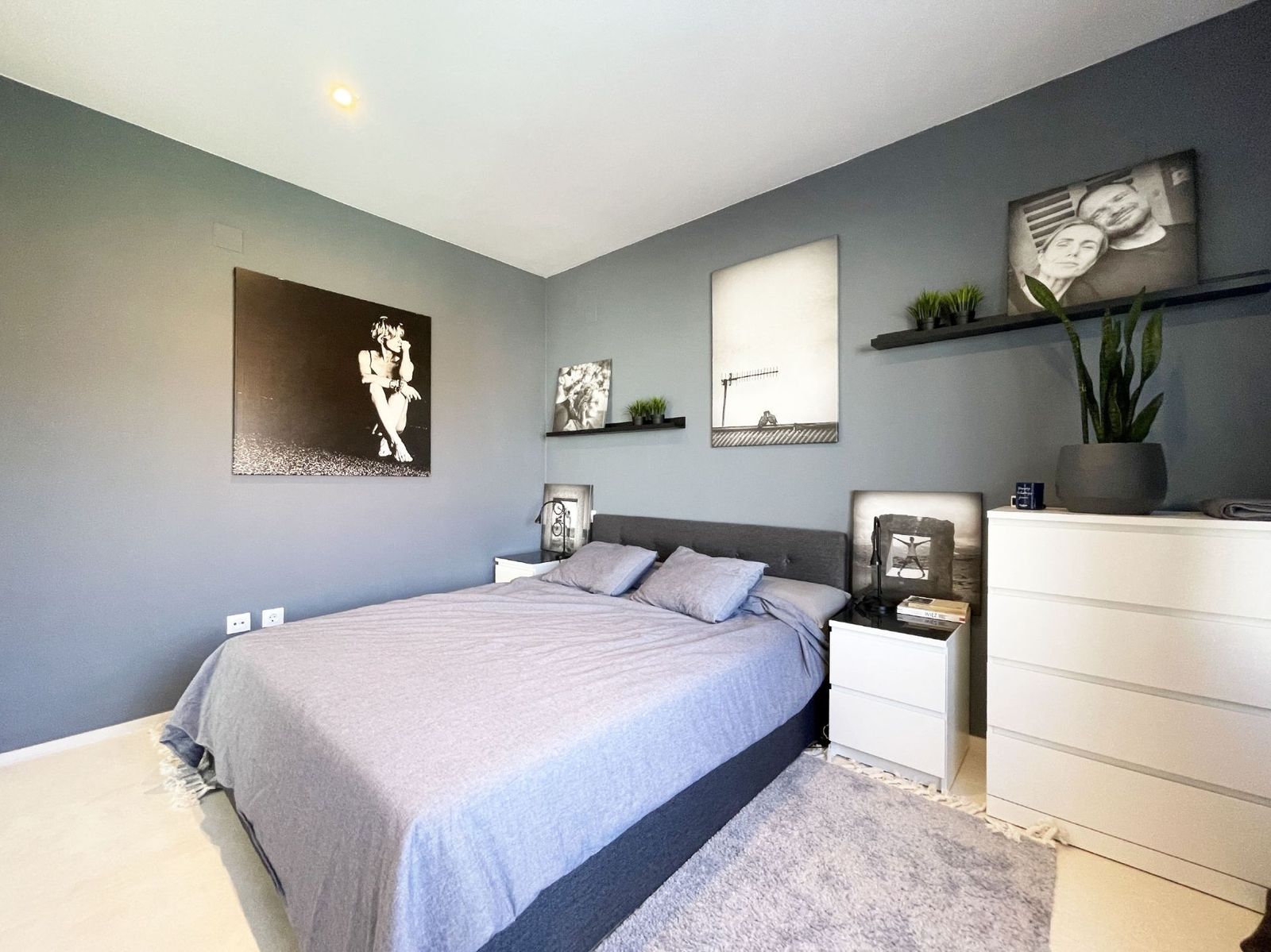 Moderne slaapkamer met grijze decoratie en kunst aan de muur.