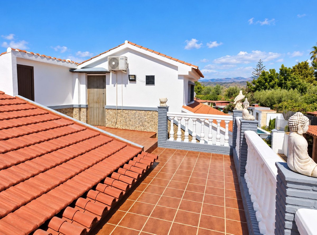Tiled terrace with a white balustrade, offering a distant view of hills and greenery. Decorated with Buddha and bird statues.