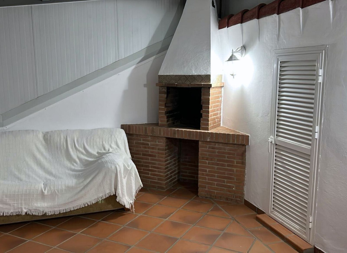 Interieur met open haard, bank met laken en tegelvloer