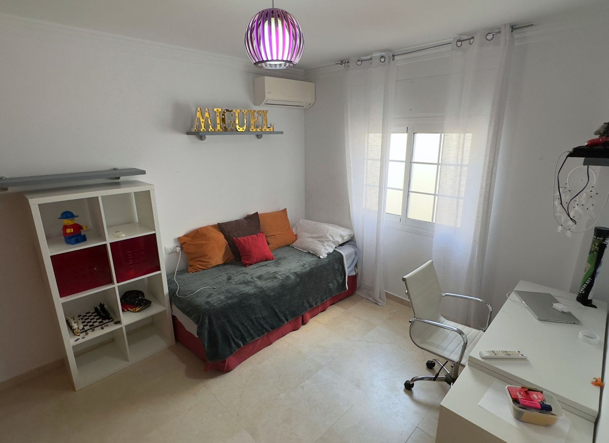 Lichte slaapkamer met bureau en bedbank.