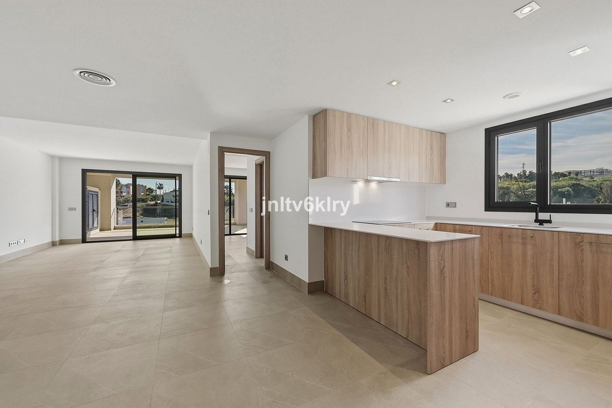 Modern open-plan living space with a sleek kitchen, island, and sliding glass doors leading to an outdoor view.