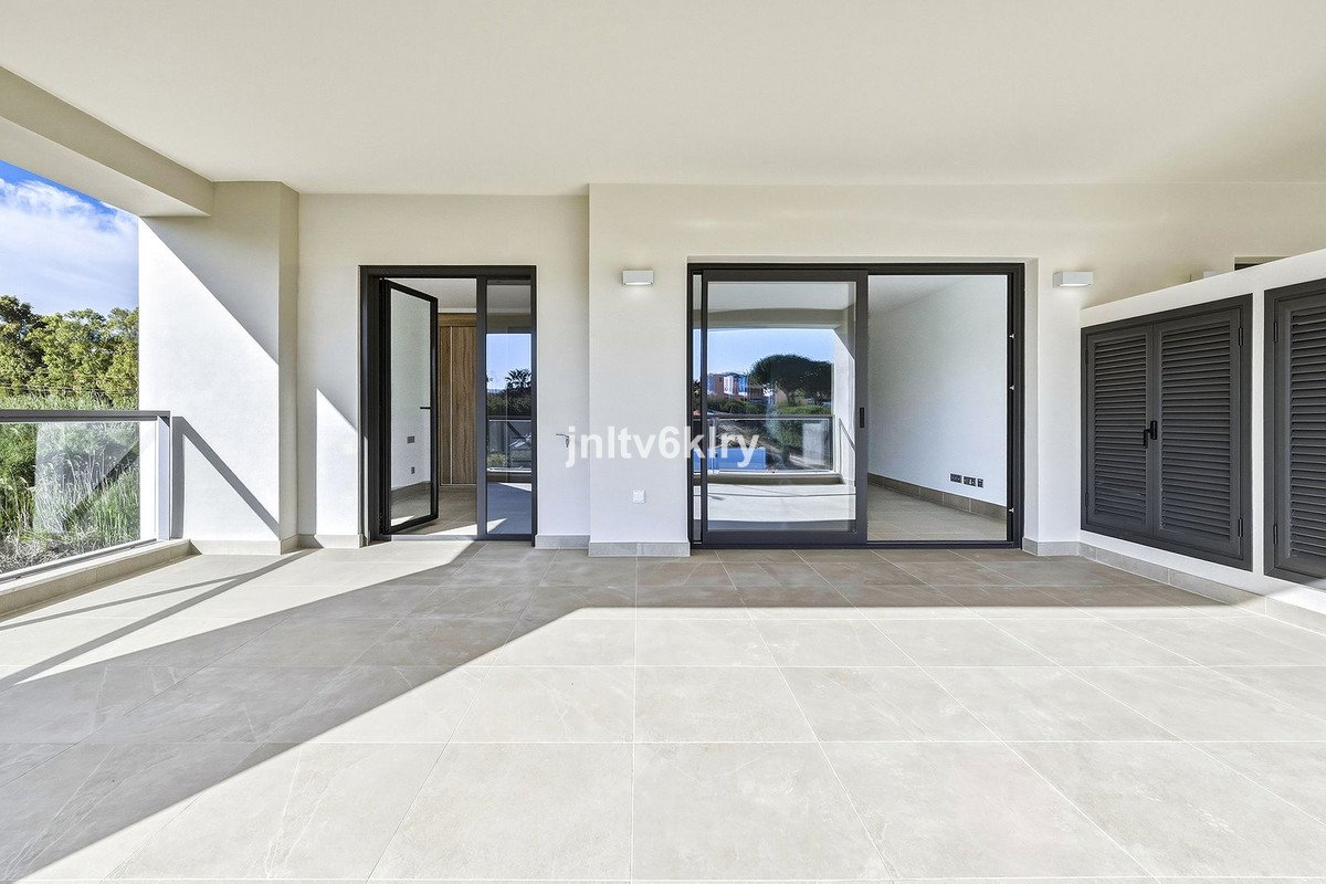 Spacious terrace with glass balcony overlooking greenery, featuring sliding doors and outdoor shutters.