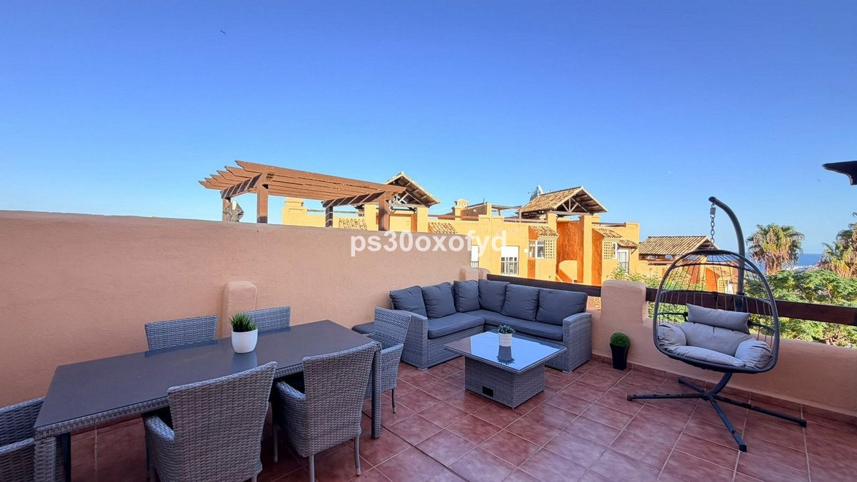 Spacious terrace with outdoor dining set, sectional sofa, coffee table, and a hanging egg chair. Buildings and greenery in the background.