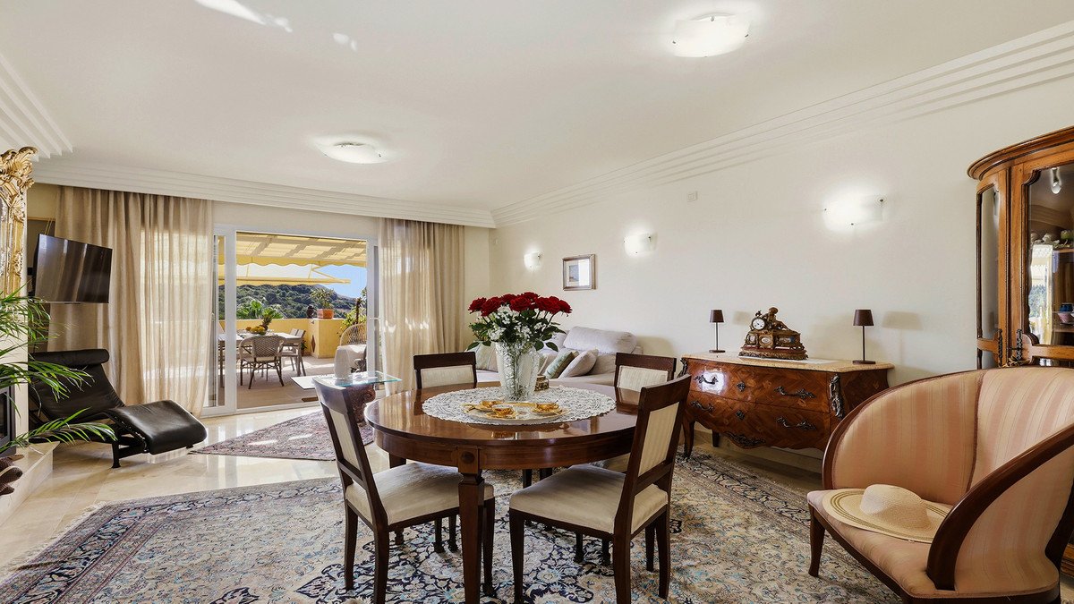 Elegant living and dining area with terrace access and beautiful outdoor views, featuring comfortable seating and a decorative fireplace.