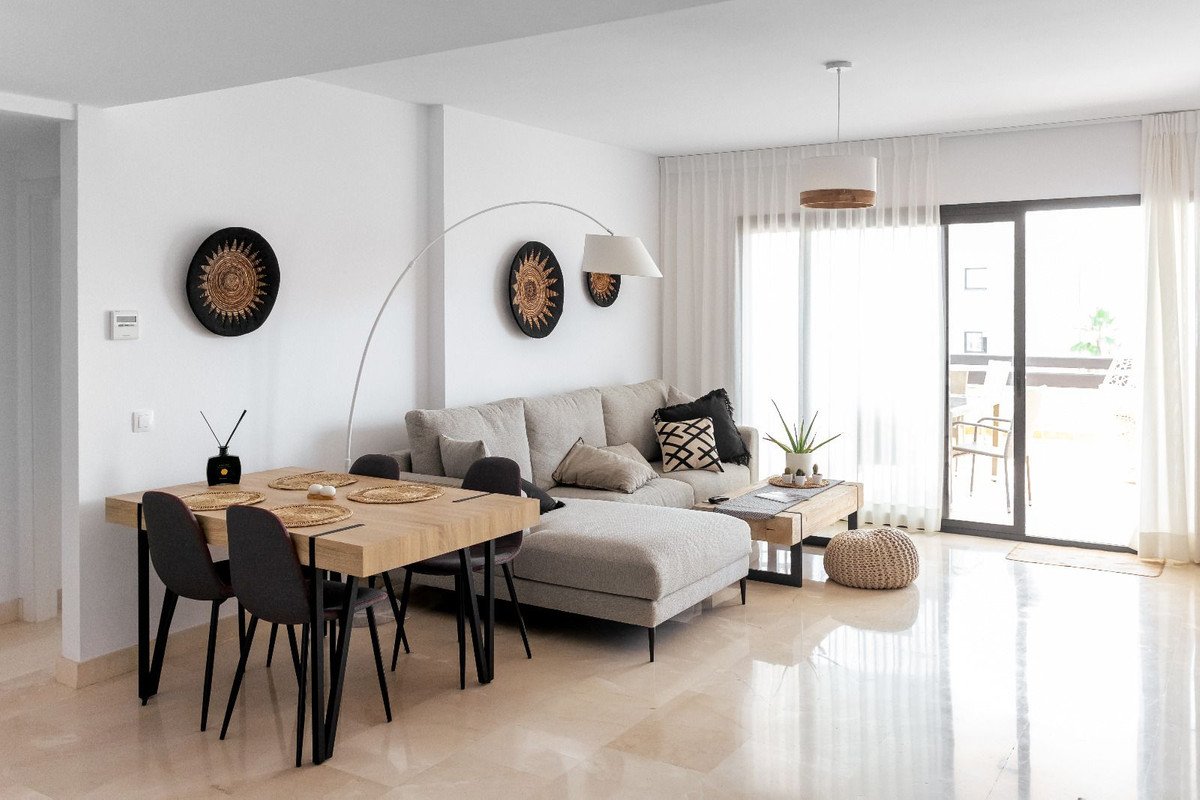 Modern living and dining area with a large sofa, wooden table, and sliding glass doors leading to a balcony.