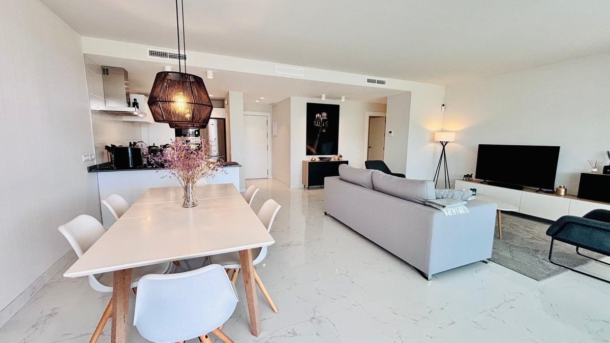 Modern living room with open-plan kitchen, grey sofa, dining table, and minimalist decor
