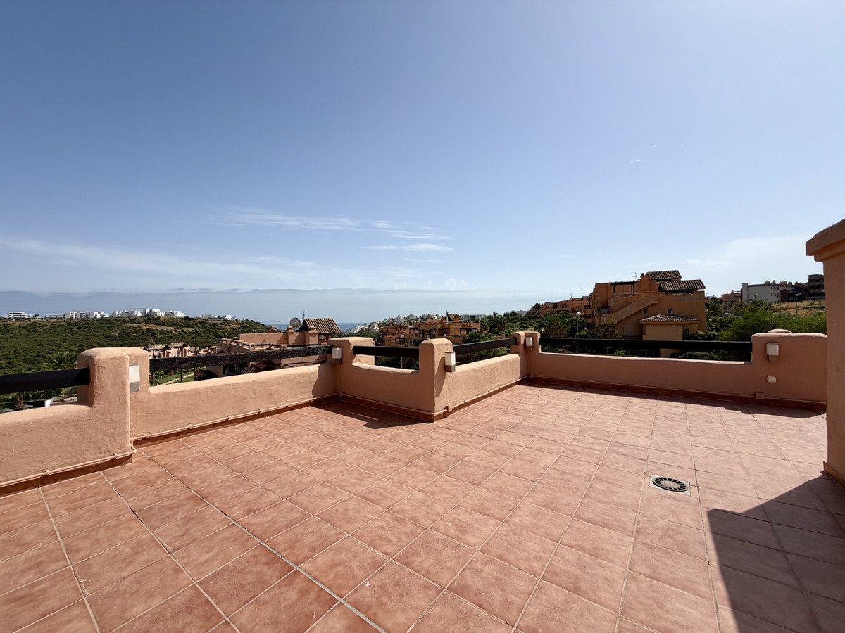 Spacious tiled terrace with a beautiful view overlooking green hills, town, and the sea under a clear blue sky.