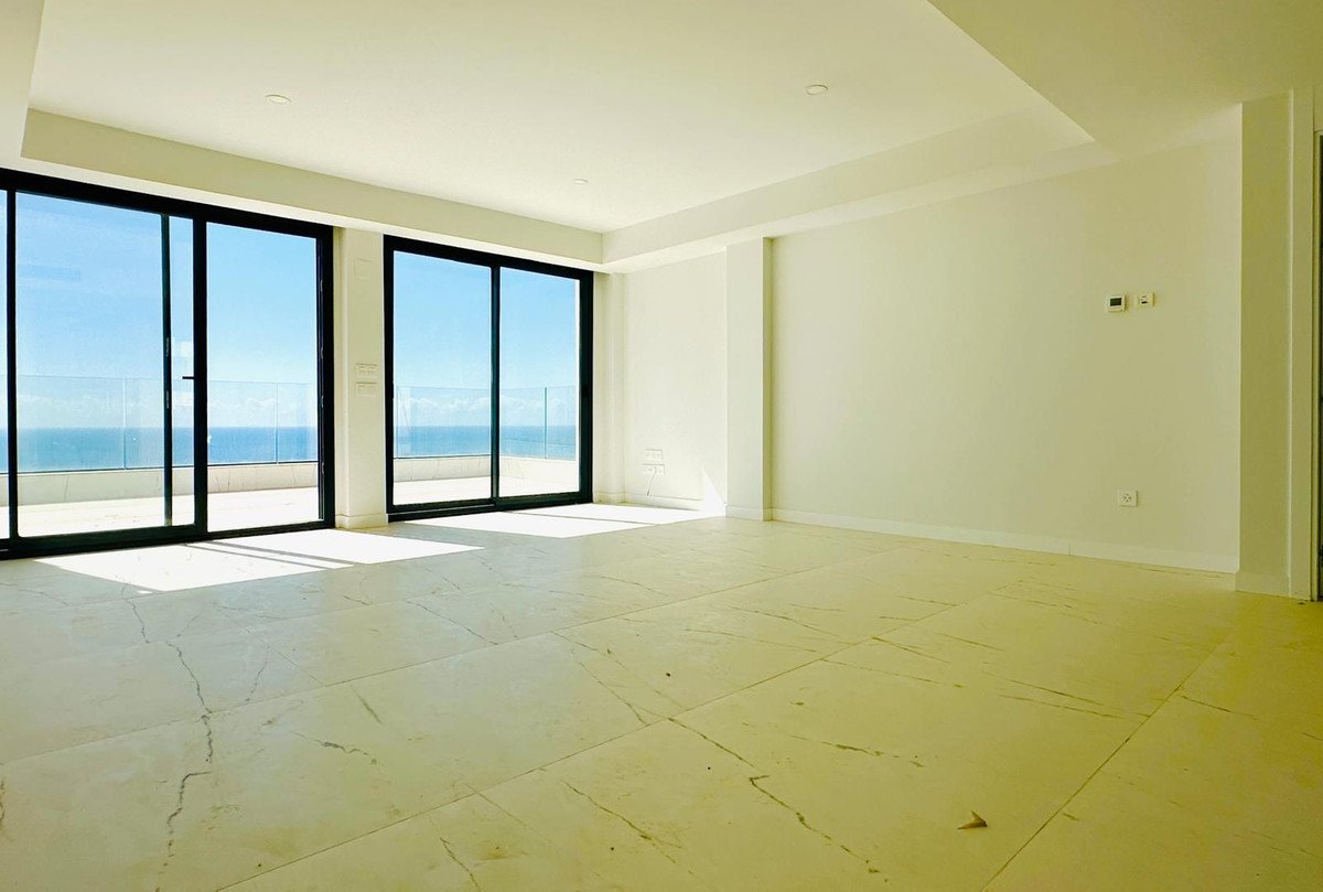 Spacious living room with floor-to-ceiling windows overlooking the ocean and a balcony.