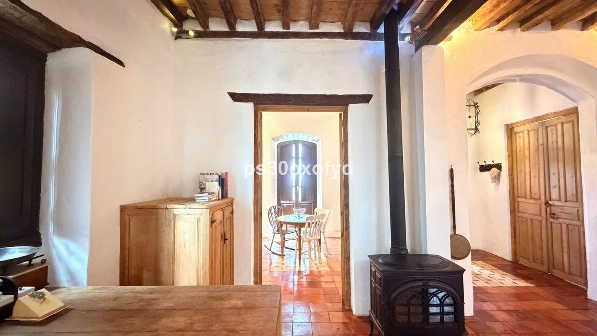 Rustic living room with a wood-burning stove, wooden cabinets, and arched doorway leading to a dining area.