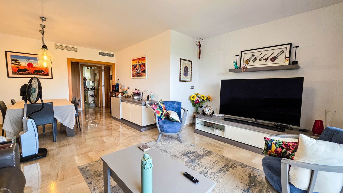 Spacious living room with marble floors, dining area, TV, and colorful decor.