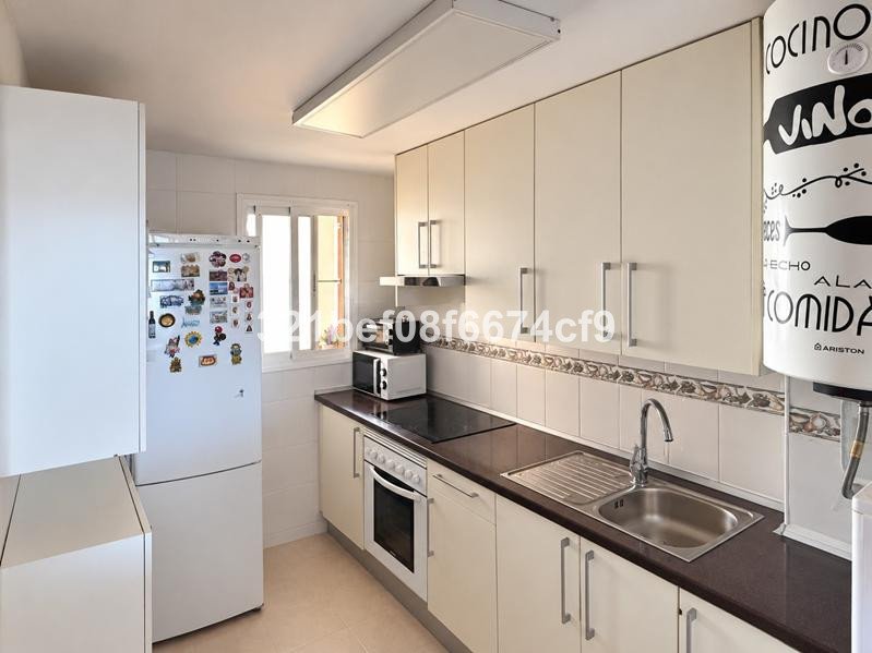 Modern kitchen with white cabinets, refrigerator, oven, sink, and microwave. Clean and functional design.