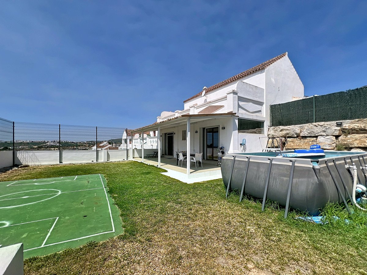 Spacious outdoor area with a swimming pool, a sports court, and a covered patio overlooking a distant town.