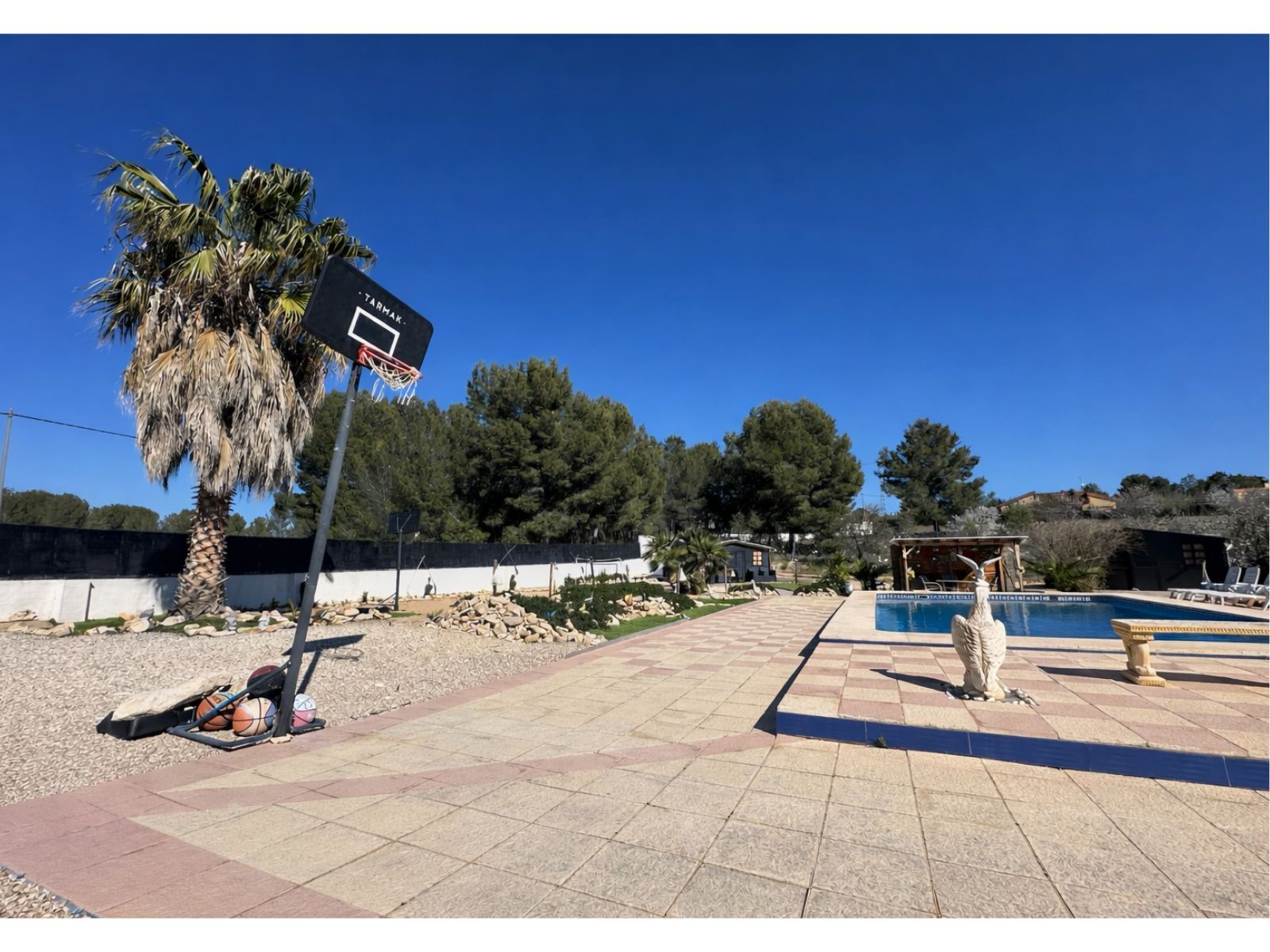 Buitenkant van een woning met zwembad en basketbalveld.