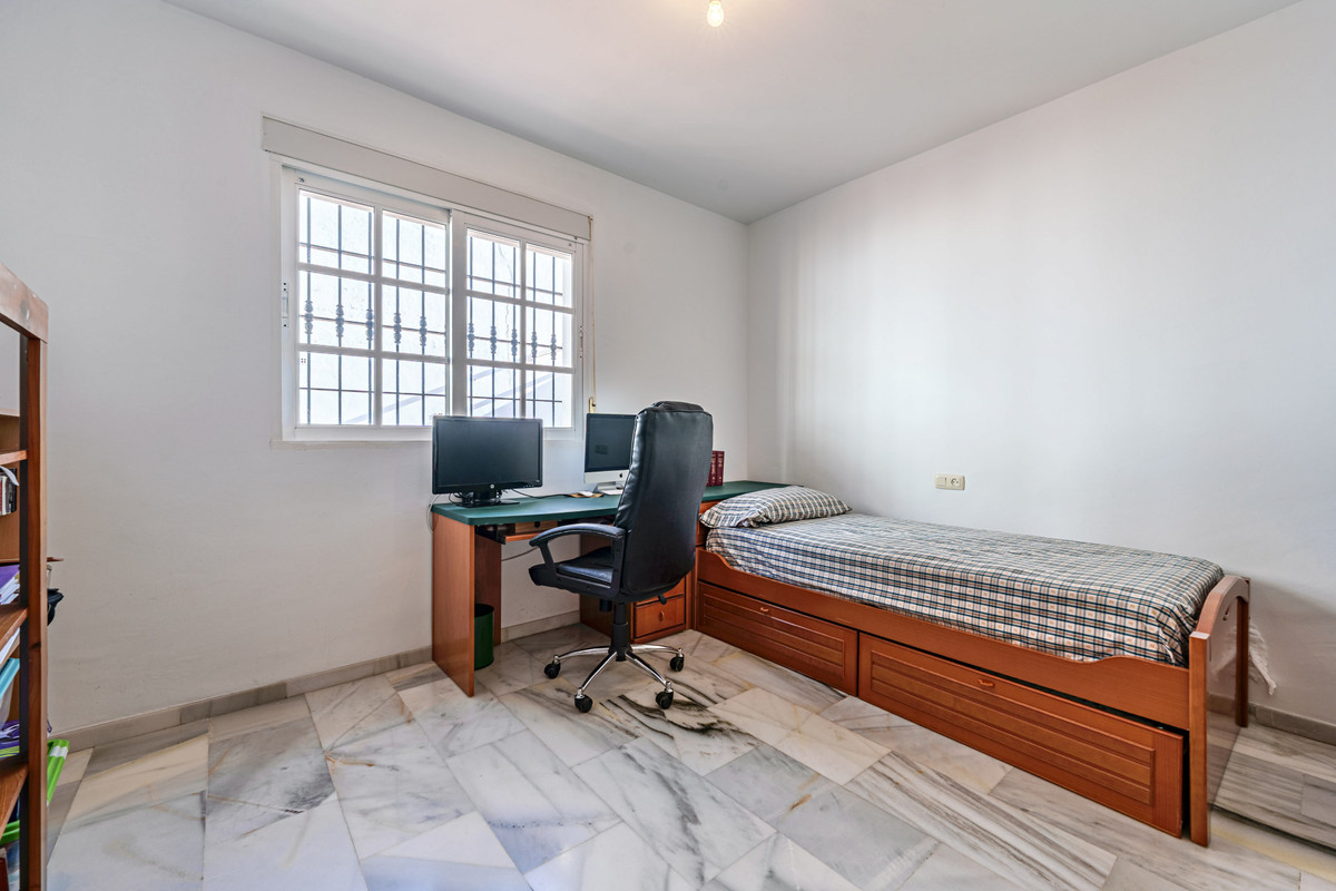 Slaapkamer met bureau, computer en eenpersoonsbed.