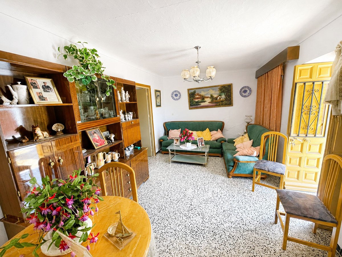 Cozy living room with green sofa, yellow curtains, and a wooden dining table with flowers