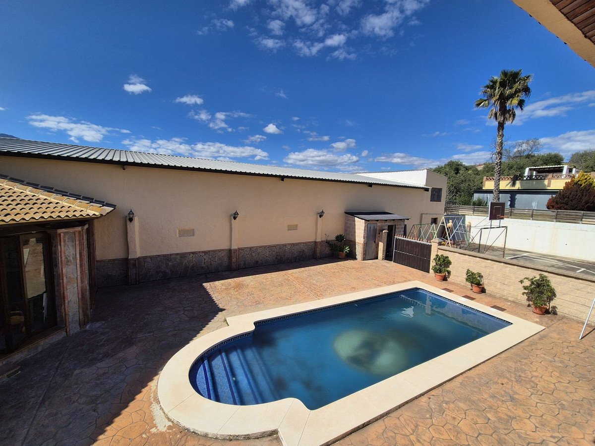 Swimming pool outside a beach house with palm tree and clear blue sky