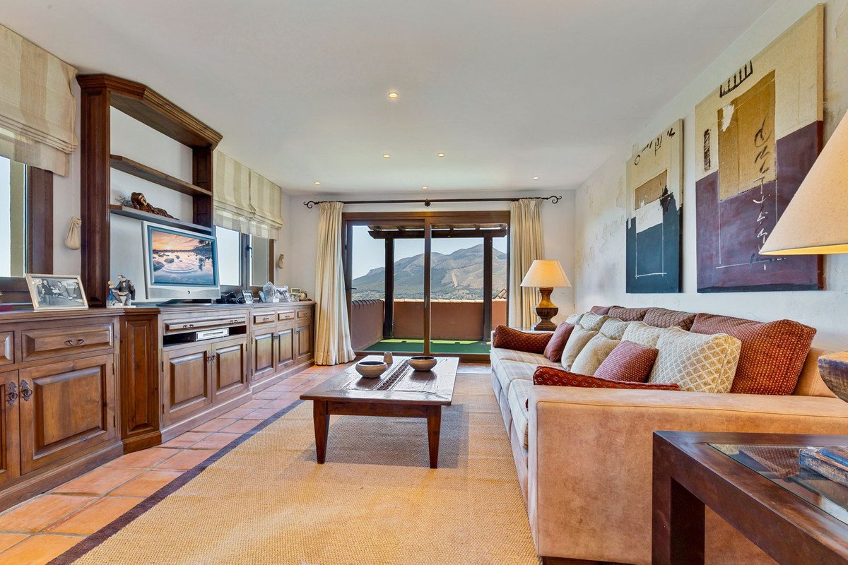 Living room with wooden furniture, TV, and mountain view through glass doors