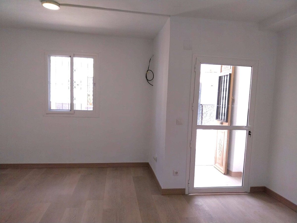 Empty room with light wood flooring, white walls, a window, and a glass door leading outside.