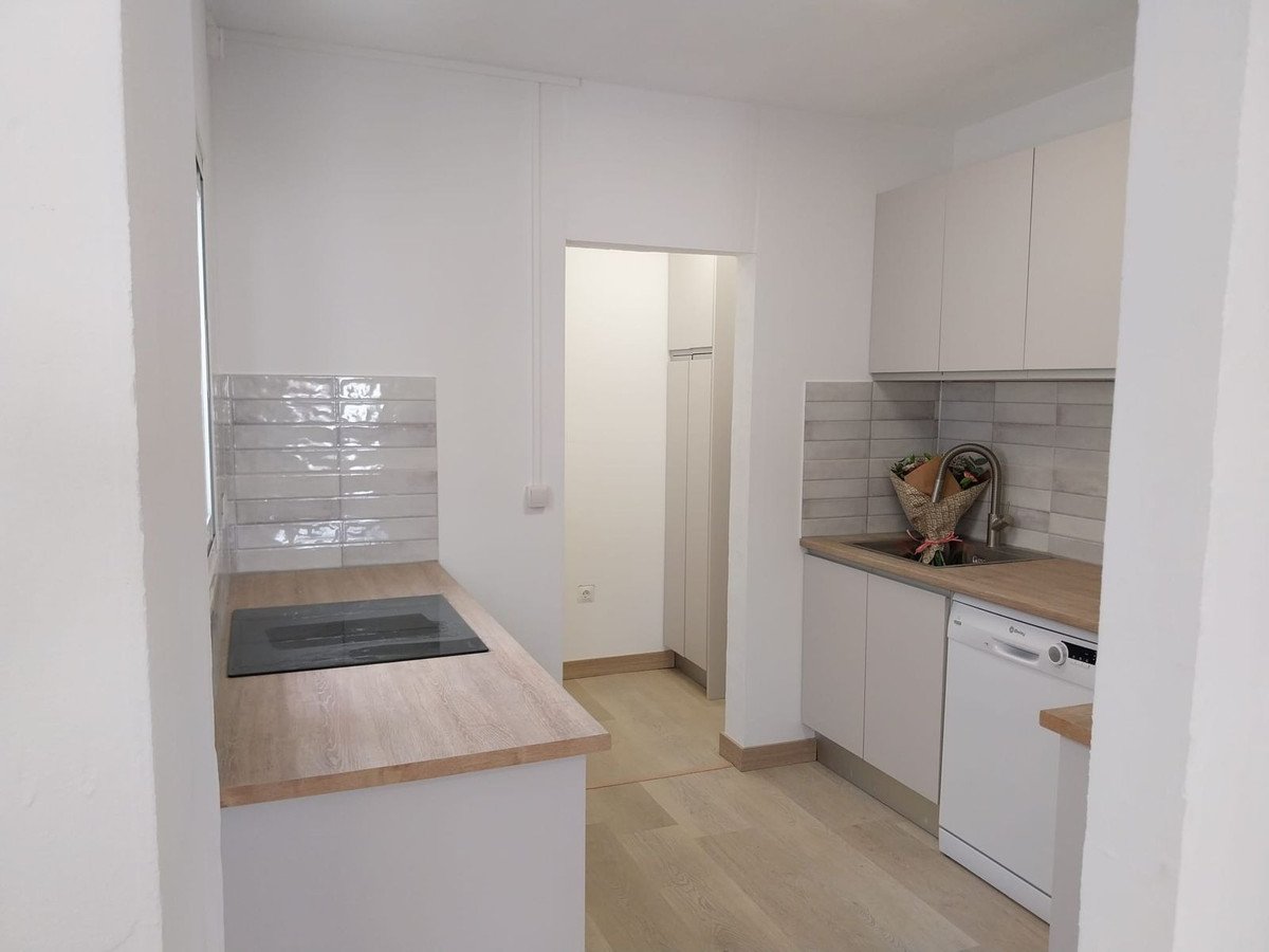 Modern kitchen with white cabinets, wooden countertops, and light wood flooring.