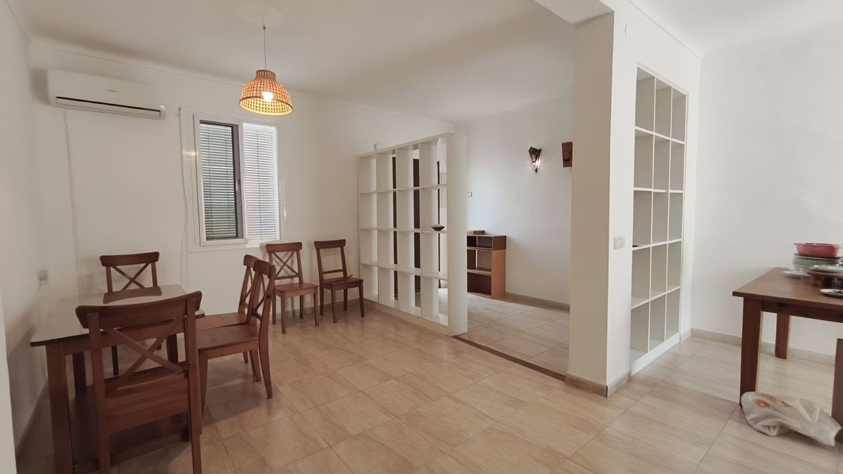 Modern living room with dining table and wooden chairs near large windows