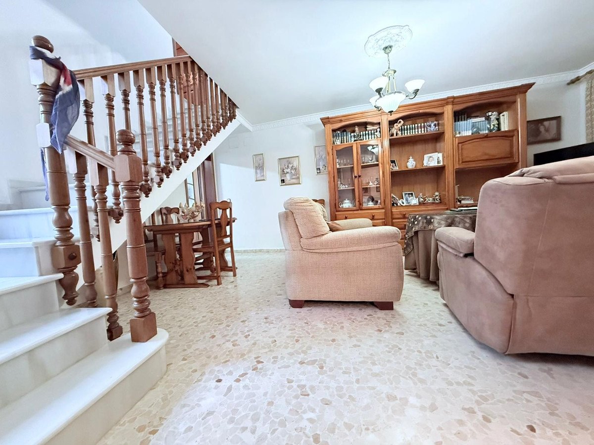 Living room with beige sofas, wooden staircase, and built-in bookshelves