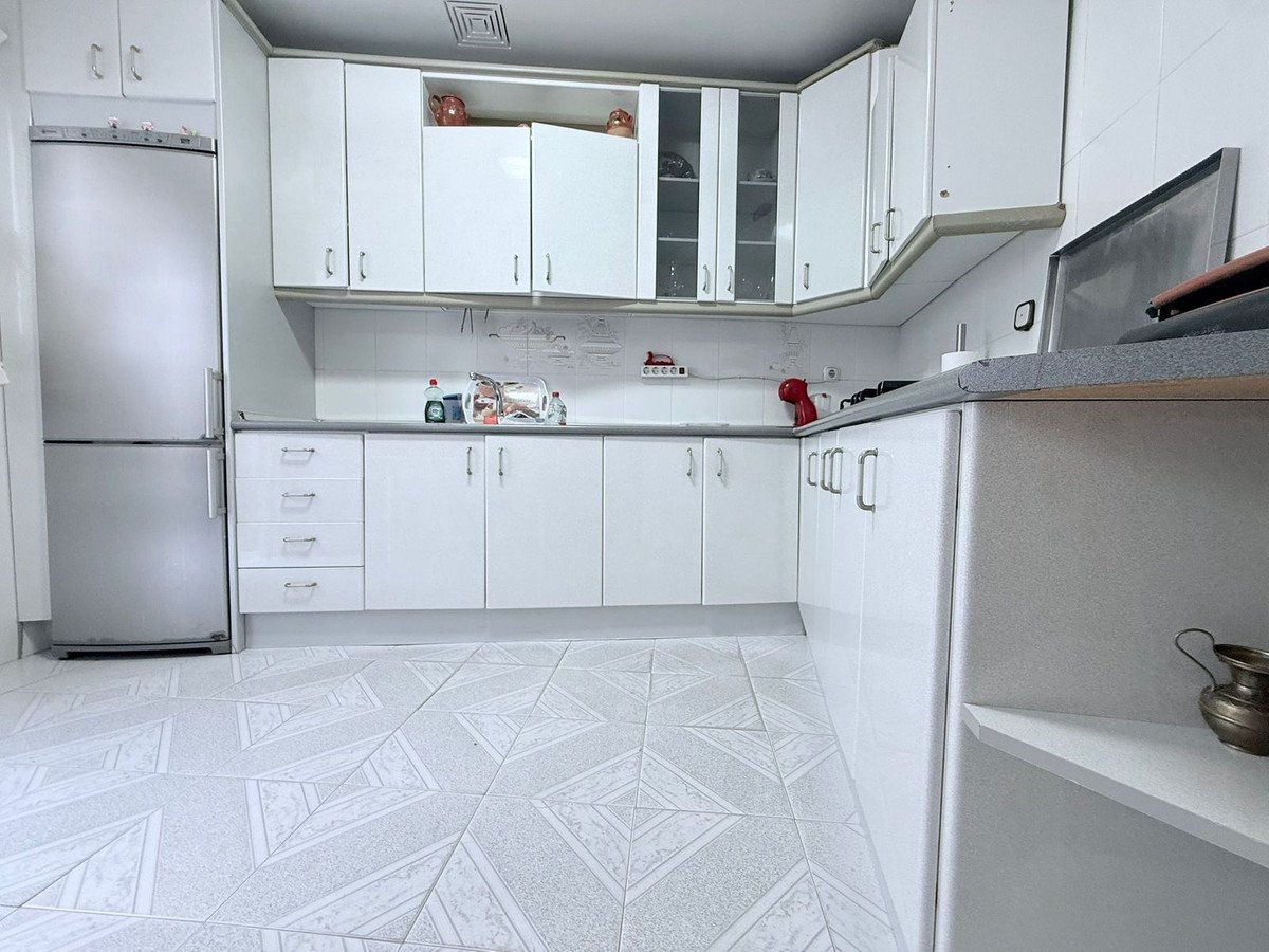 Modern white kitchen with tile floor and stainless steel appliances