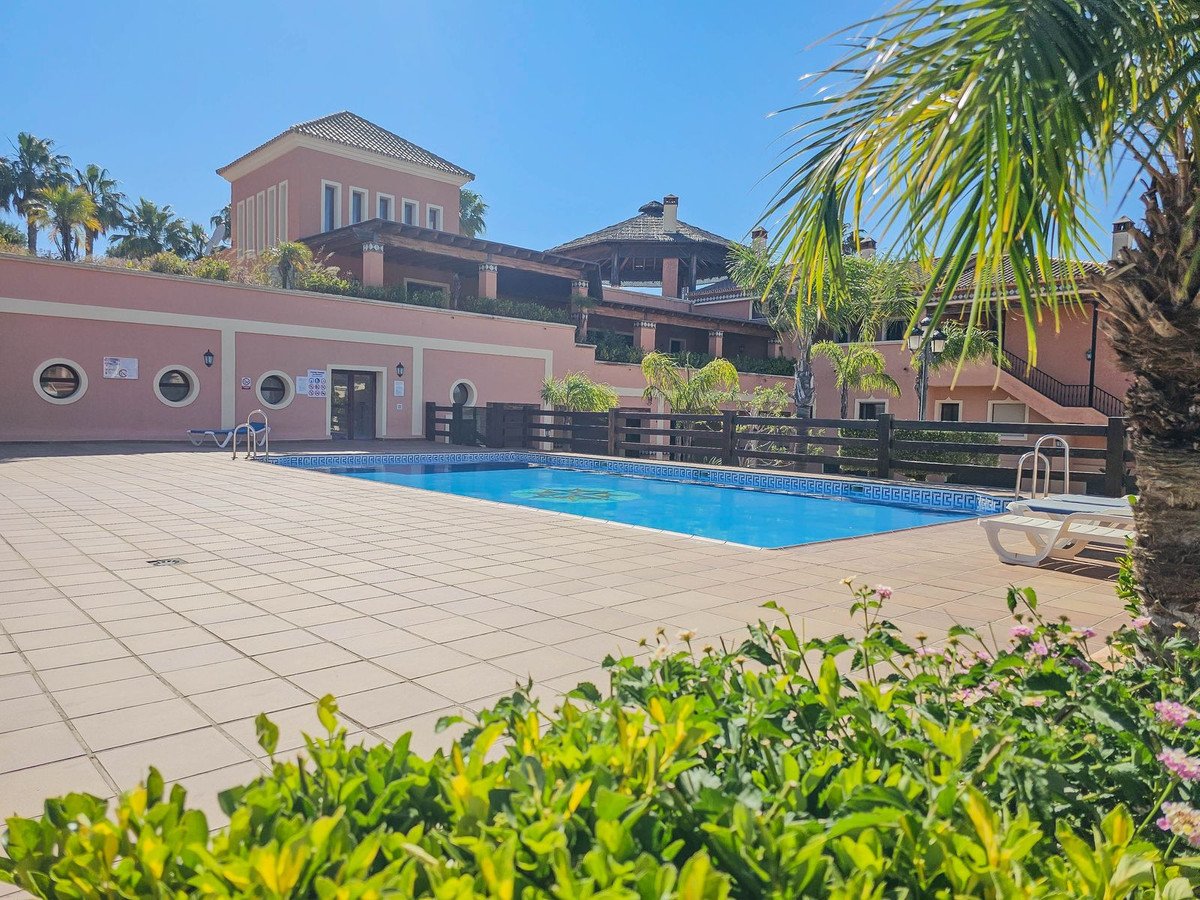 Villa with pool, palm trees, and tiled patio under clear blue sky.