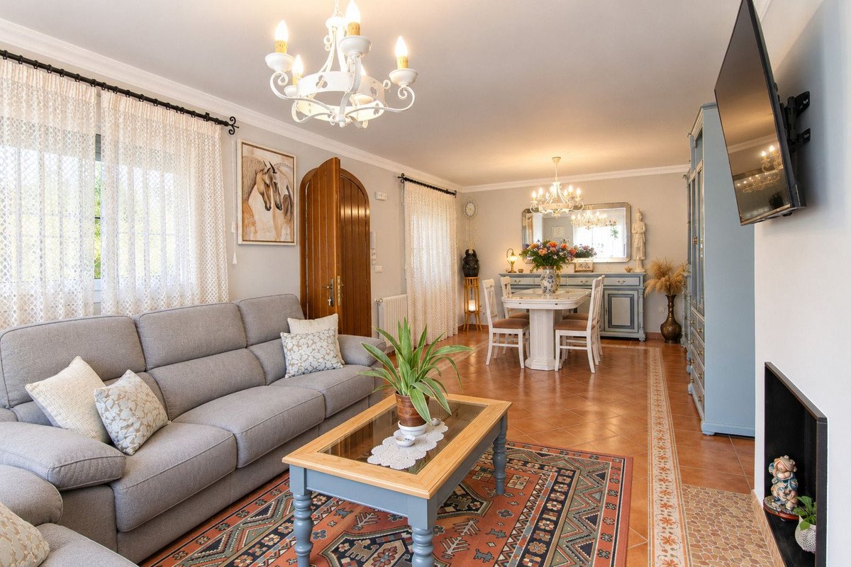 Elegant living and dining room with a sofa, dining table, chandelier, and fireplace.