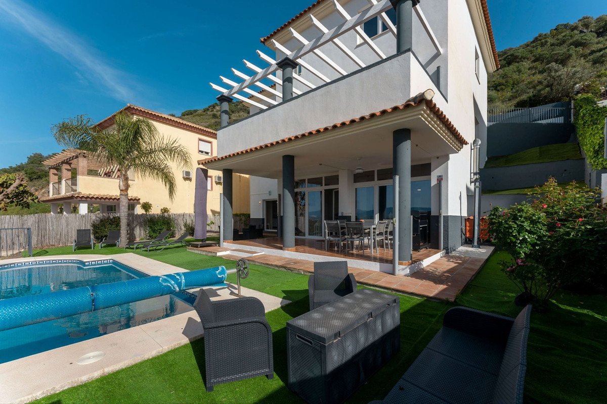 Modern villa with private pool, patio, and mountain views under a clear blue sky.